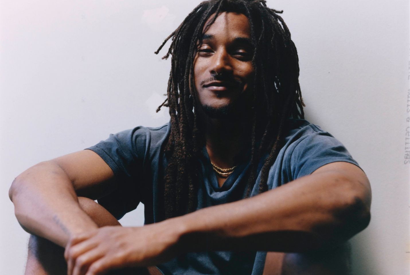 Jordan Ward sat on the ground wearing a blue tshirt and gold chain